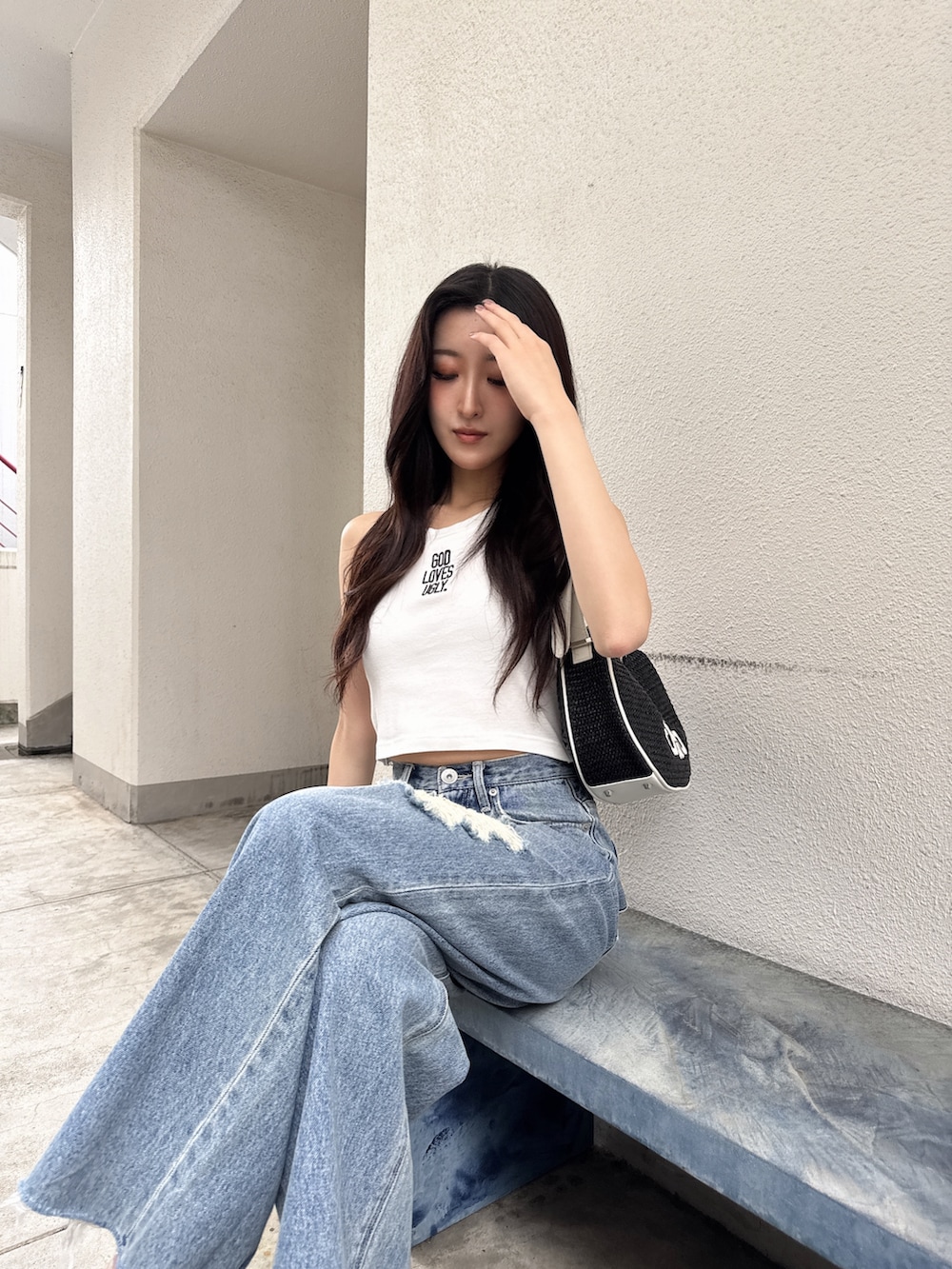 ホワイト系のタンクトップ、ブルー系のデニムパンツ、ホワイト系のパンプスを着用したレディースの夏コーディネートの3枚目の写真