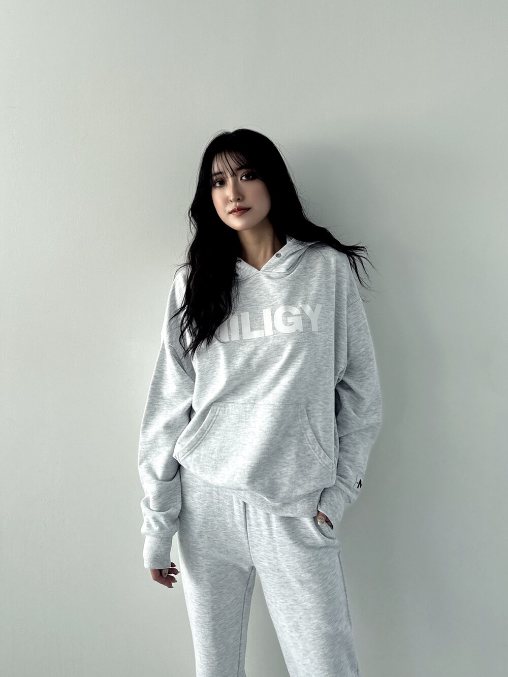 グレー系のパーカー、グレー系のスウェットパンツ、ホワイト系のパンプスを着用したレディースの秋コーディネートの3枚目の写真