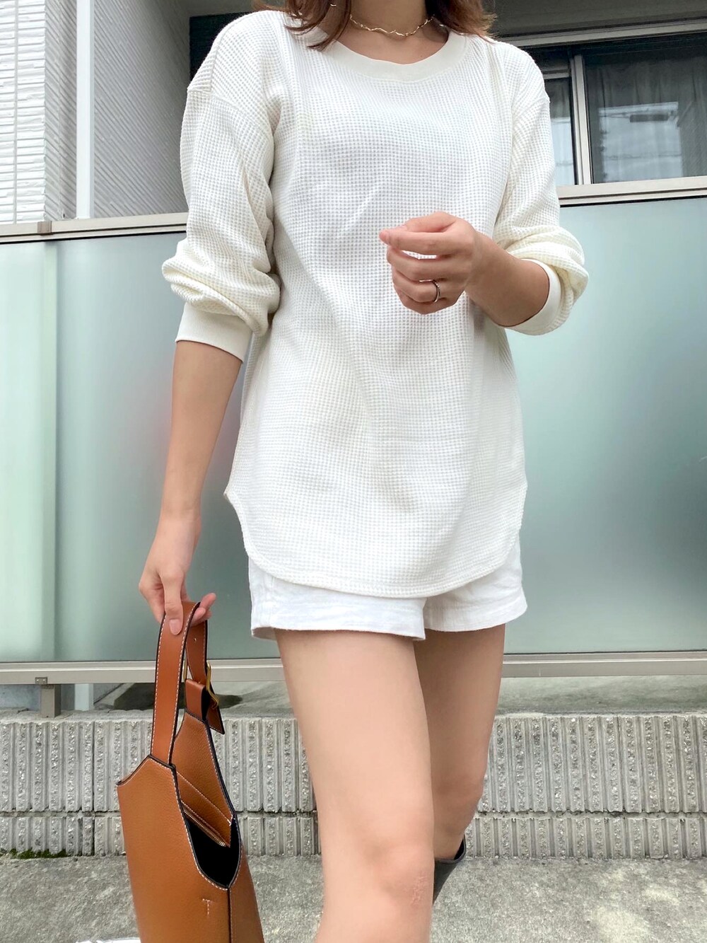 ホワイト系のニット/セーター、ブラウン系のハンドバッグ、ホワイト系のパンツを着用したレディースの秋コーディネートの3枚目の写真