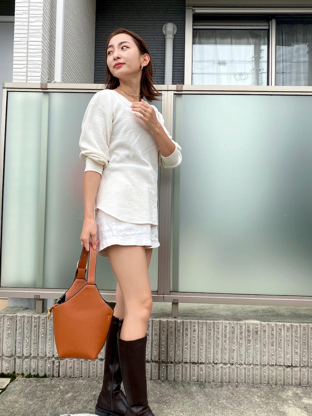 ホワイト系のニット/セーター、ブラウン系のハンドバッグ、ホワイト系のパンツを着用したレディースの秋コーディネートの2枚目の写真