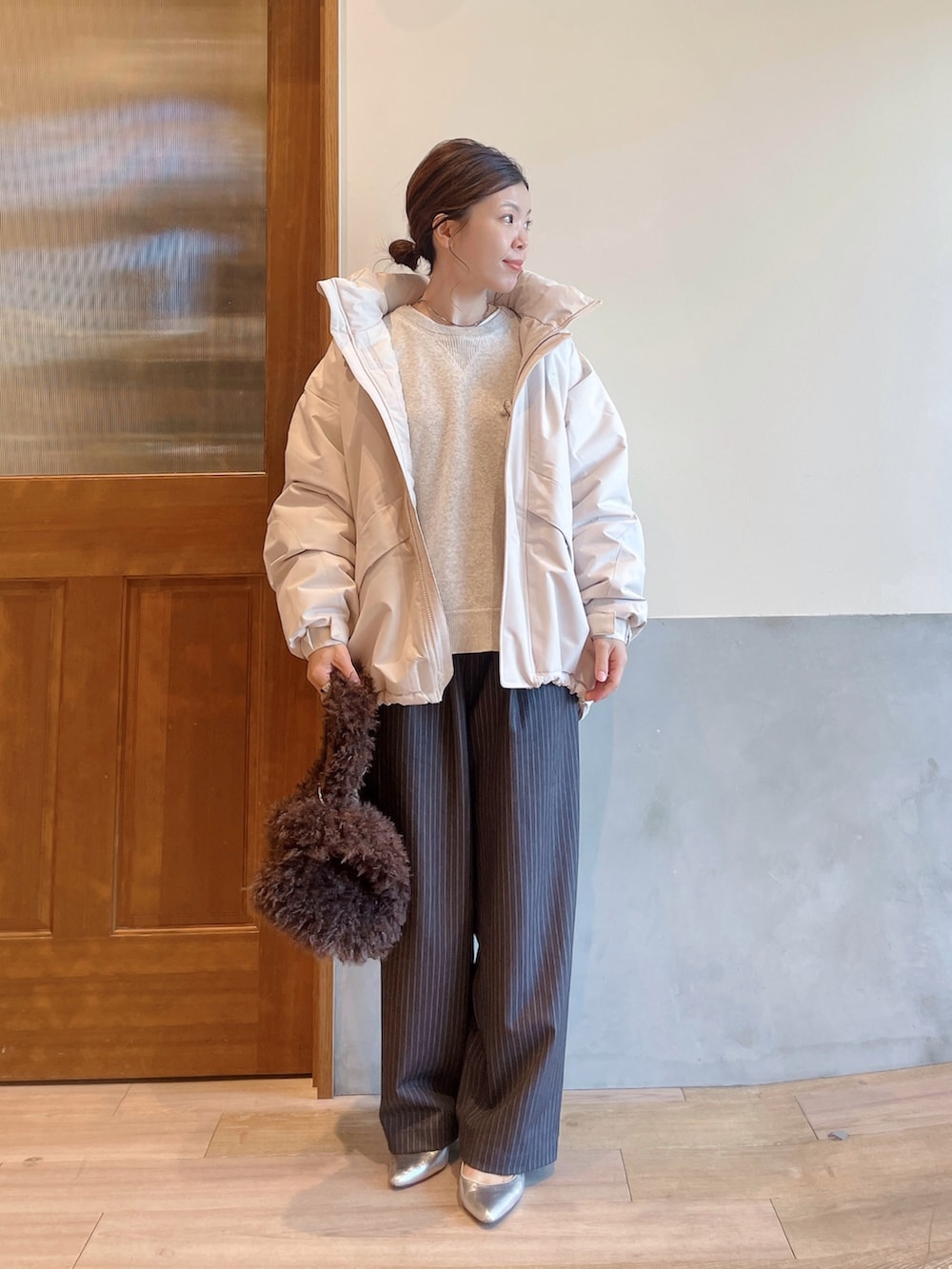 ホワイト系のダウンジャケット/コート、ホワイト系のニット/セーター、グレー系のスラックスを着用したレディースの秋コーディネートの3枚目の写真