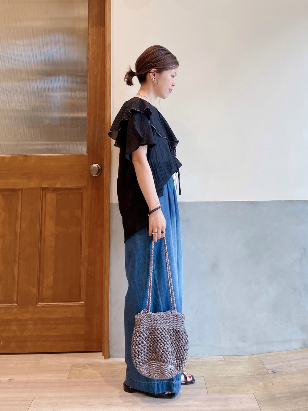 ブラック系のシャツ/ブラウス、ブルー系のデニムパンツ、その他のトートバッグを着用したレディースの夏コーディネートの2枚目の写真