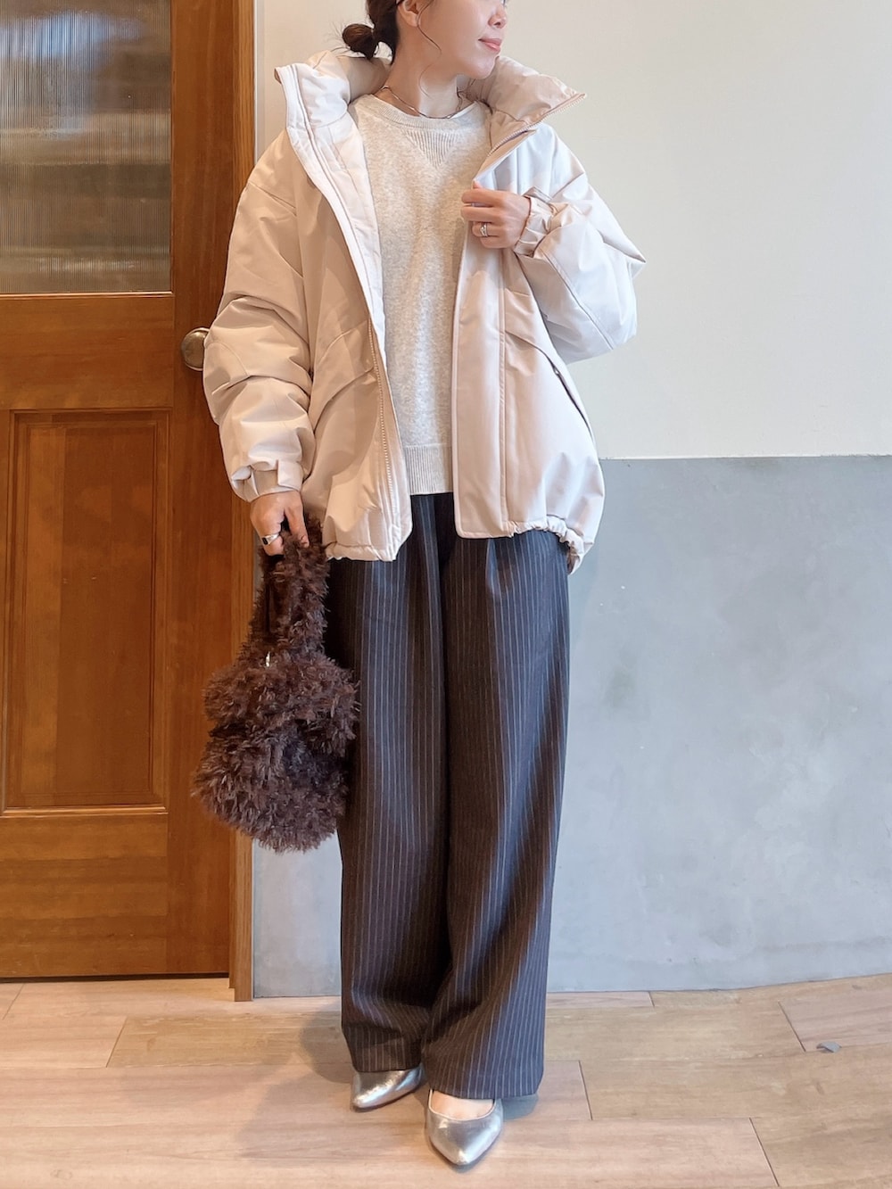 ホワイト系のダウンジャケット/コート、ホワイト系のニット/セーター、グレー系のスラックスを着用したレディースの秋コーディネートの4枚目の写真