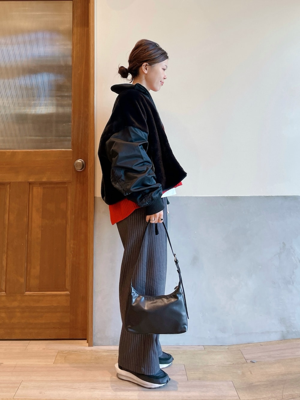 レッド系のニット/セーター、ブラック系のブルゾン、グレー系のスラックスを着用したレディースの冬コーディネートの2枚目の写真