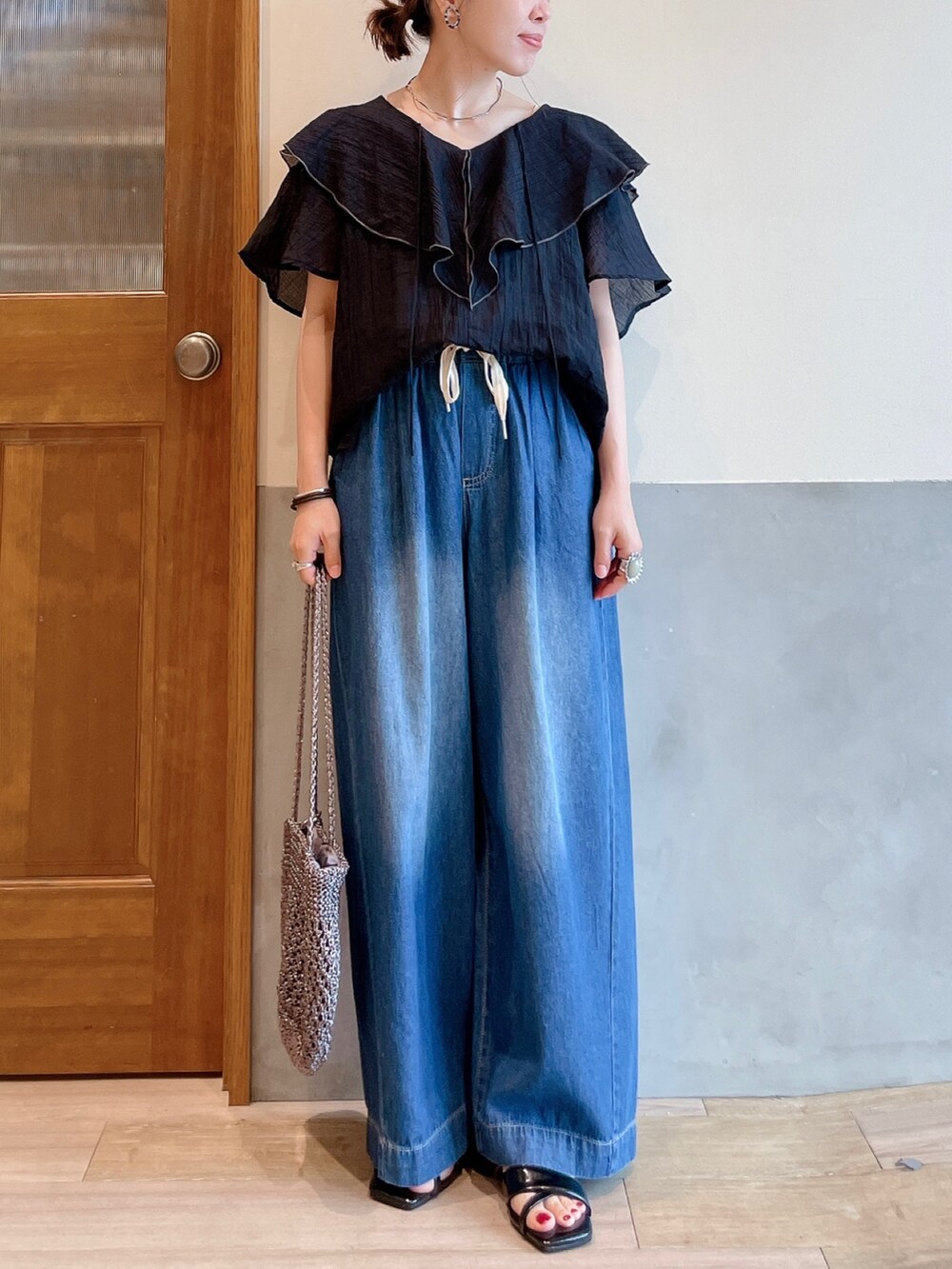 ブラック系のシャツ/ブラウス、ブルー系のデニムパンツ、その他のトートバッグを着用したレディースの夏コーディネートの3枚目の写真