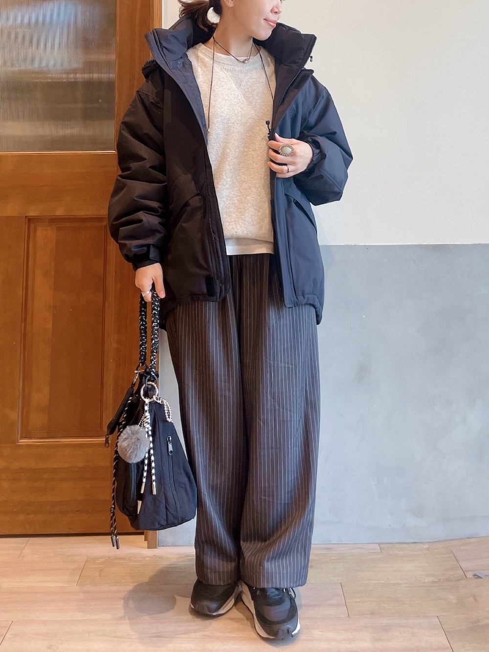 ホワイト系のニット/セーター、ブラック系のダウンジャケット/コート、グレー系のスラックスを着用したレディースの秋コーディネートの3枚目の写真
