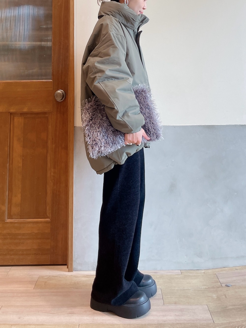 グリーン系のダウンジャケット/コート、ホワイト系のニット/セーター、グレー系のトートバッグを着用したレディースの秋コーディネートの6枚目の写真