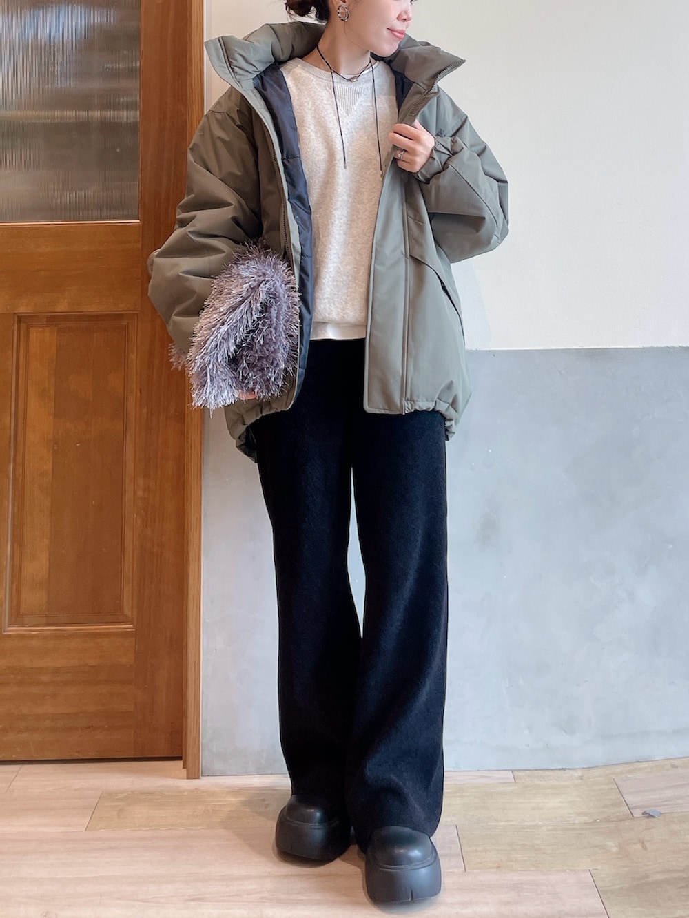 グリーン系のダウンジャケット/コート、ホワイト系のニット/セーター、グレー系のトートバッグを着用したレディースの秋コーディネートの4枚目の写真