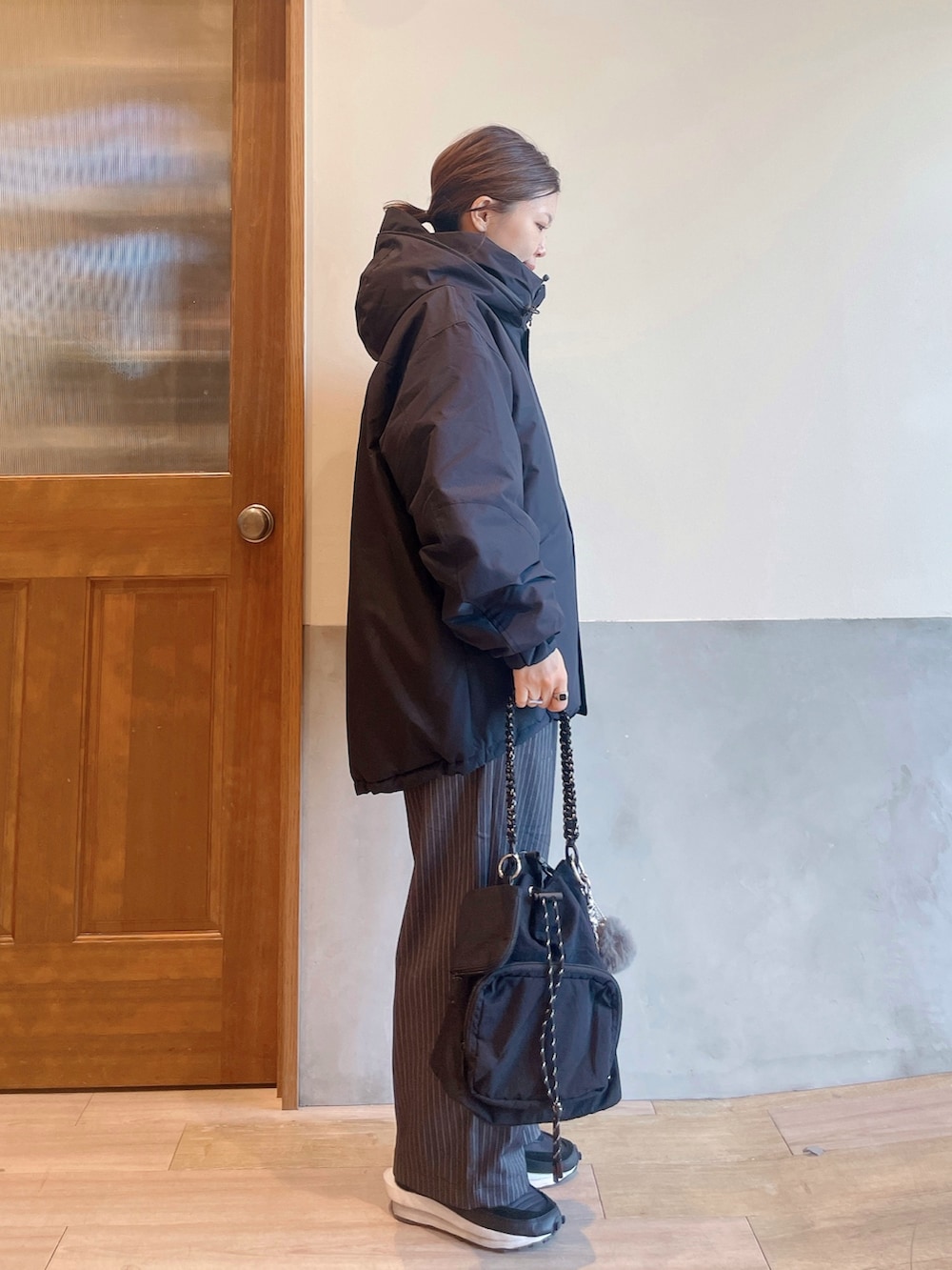 ホワイト系のニット/セーター、ブラック系のダウンジャケット/コート、グレー系のスラックスを着用したレディースの秋コーディネートの2枚目の写真