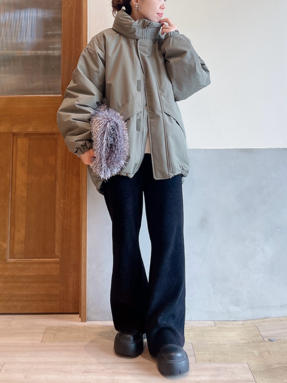 グリーン系のダウンジャケット/コート、ホワイト系のニット/セーター、グレー系のトートバッグを着用したレディースの秋コーディネートの5枚目の写真