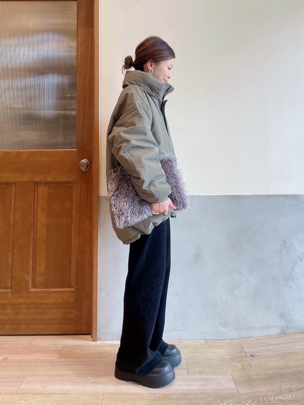 グリーン系のダウンジャケット/コート、ホワイト系のニット/セーター、グレー系のトートバッグを着用したレディースの秋コーディネートの3枚目の写真