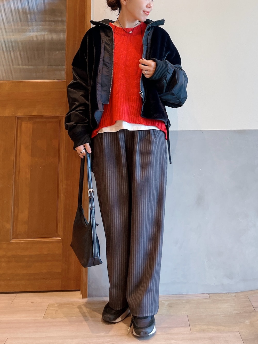 レッド系のニット/セーター、ブラック系のブルゾン、グレー系のスラックスを着用したレディースの冬コーディネートの3枚目の写真