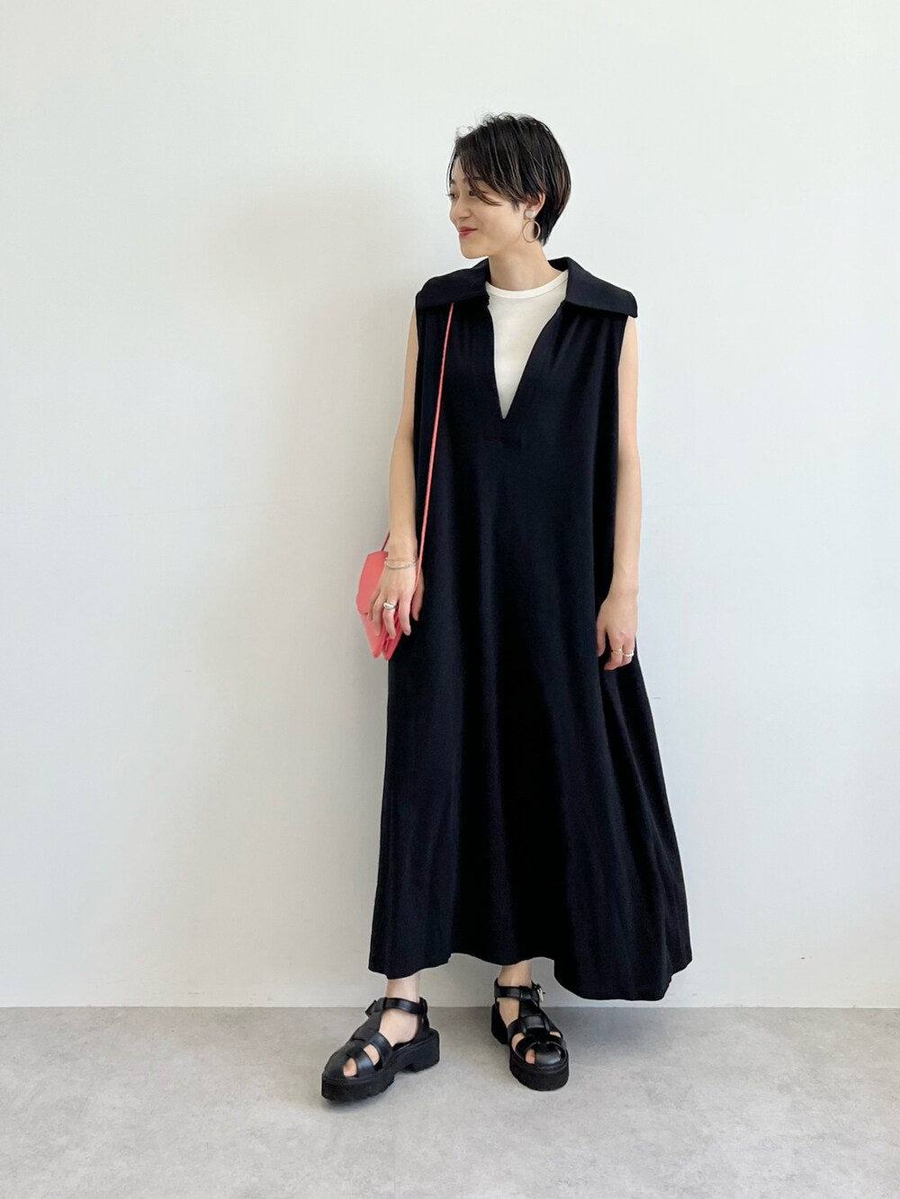 ブラック系のワンピース、ピンク系のショルダーバッグ、ブラック系のサンダルを着用したレディースの春コーディネートの2枚目の写真