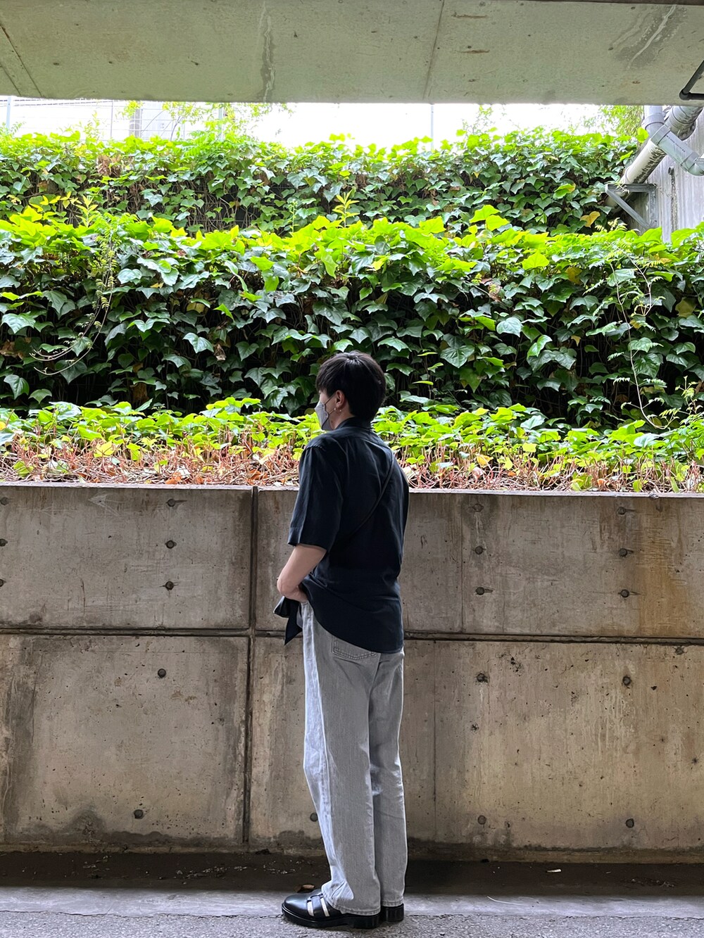 シルバー系のデニムパンツ、ブラック系のサンダル、ブラック系のショルダーバッグを着用したメンズの春コーディネートの2枚目の写真