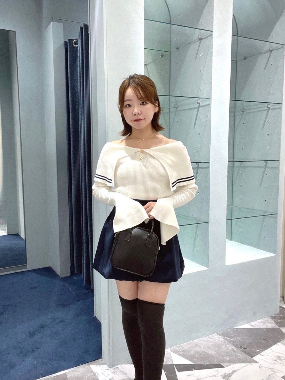 ホワイト系のニット/セーター、ブルー系のスカート、ブラック系のボストンバッグを着用したレディースの春コーディネートの5枚目の写真