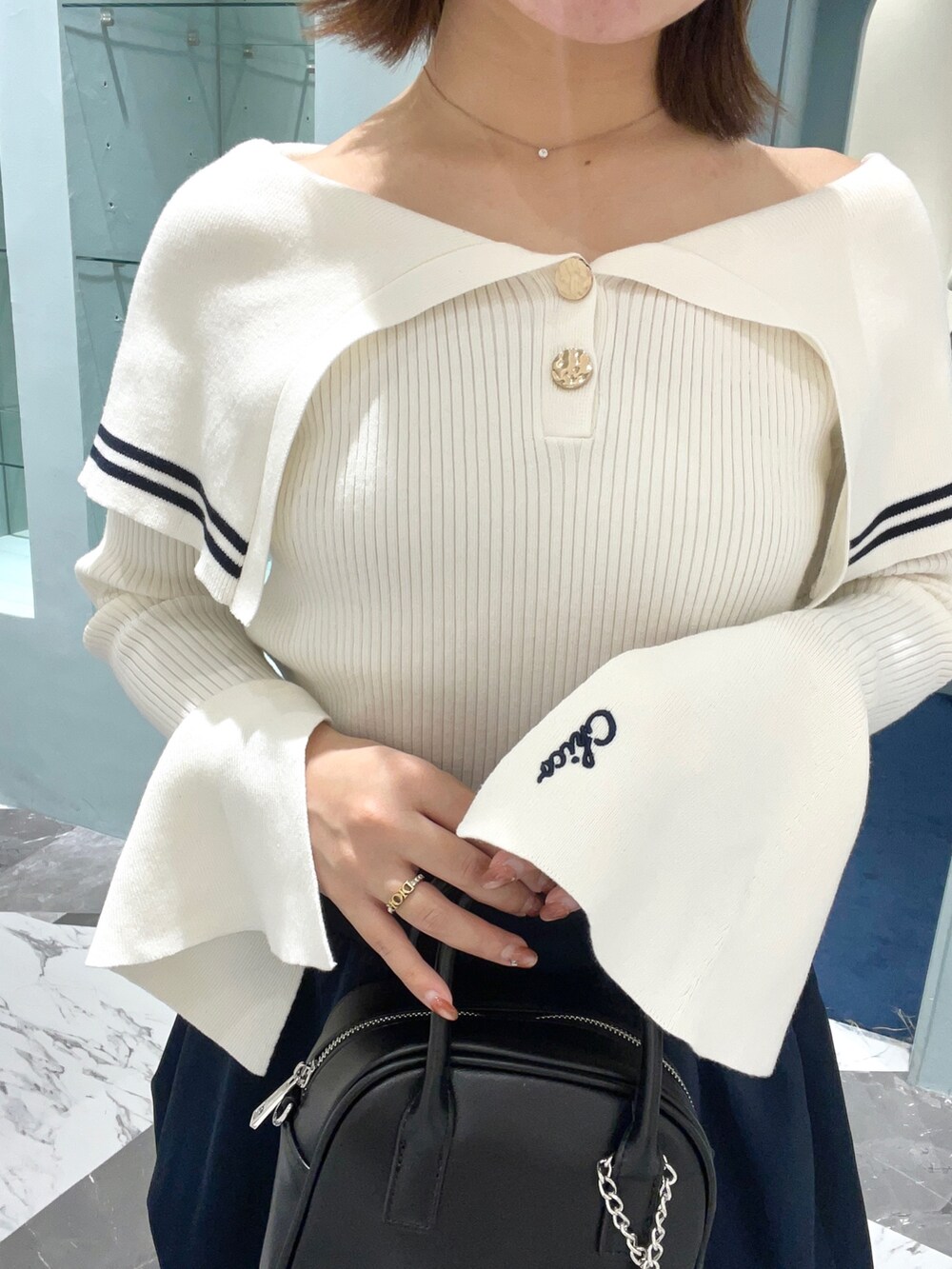 ホワイト系のニット/セーター、ブルー系のスカート、ブラック系のボストンバッグを着用したレディースの春コーディネートの4枚目の写真