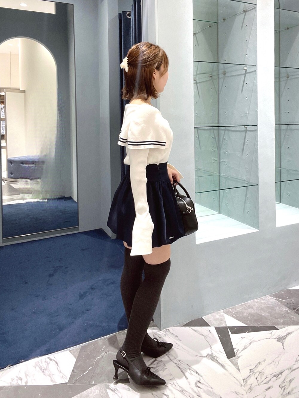 ホワイト系のニット/セーター、ブルー系のスカート、ブラック系のボストンバッグを着用したレディースの春コーディネートの2枚目の写真