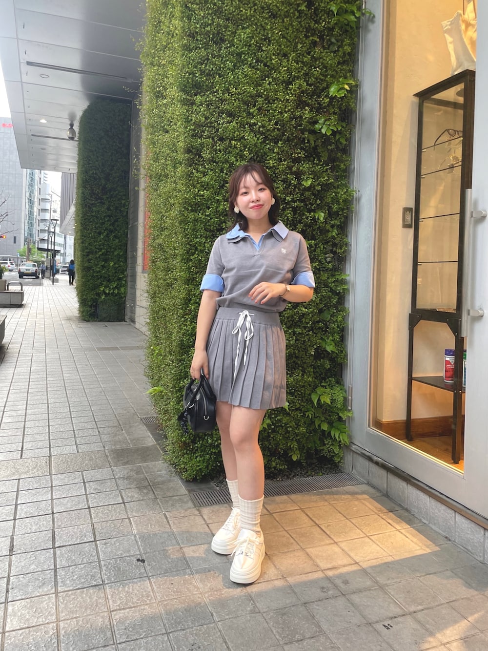 グレー系のニット/セーター、グレー系のスカート、ホワイト系のスニーカーを着用したレディースの春コーディネートの2枚目の写真