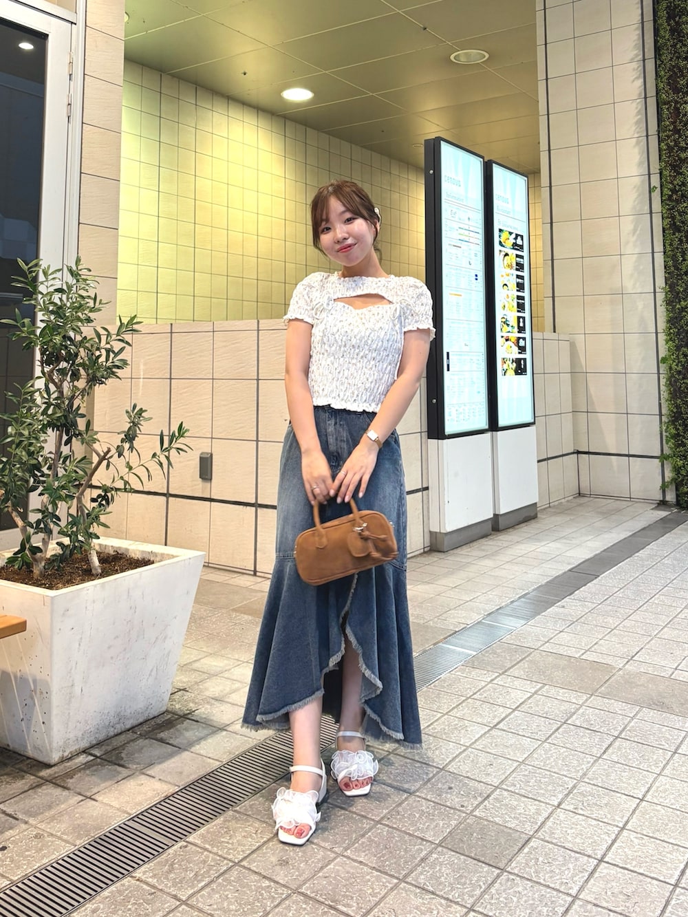 ブルー系のスカート、ホワイト系のTシャツ/カットソー、ベージュ系のボストンバッグを着用したレディースの夏コーディネートの2枚目の写真