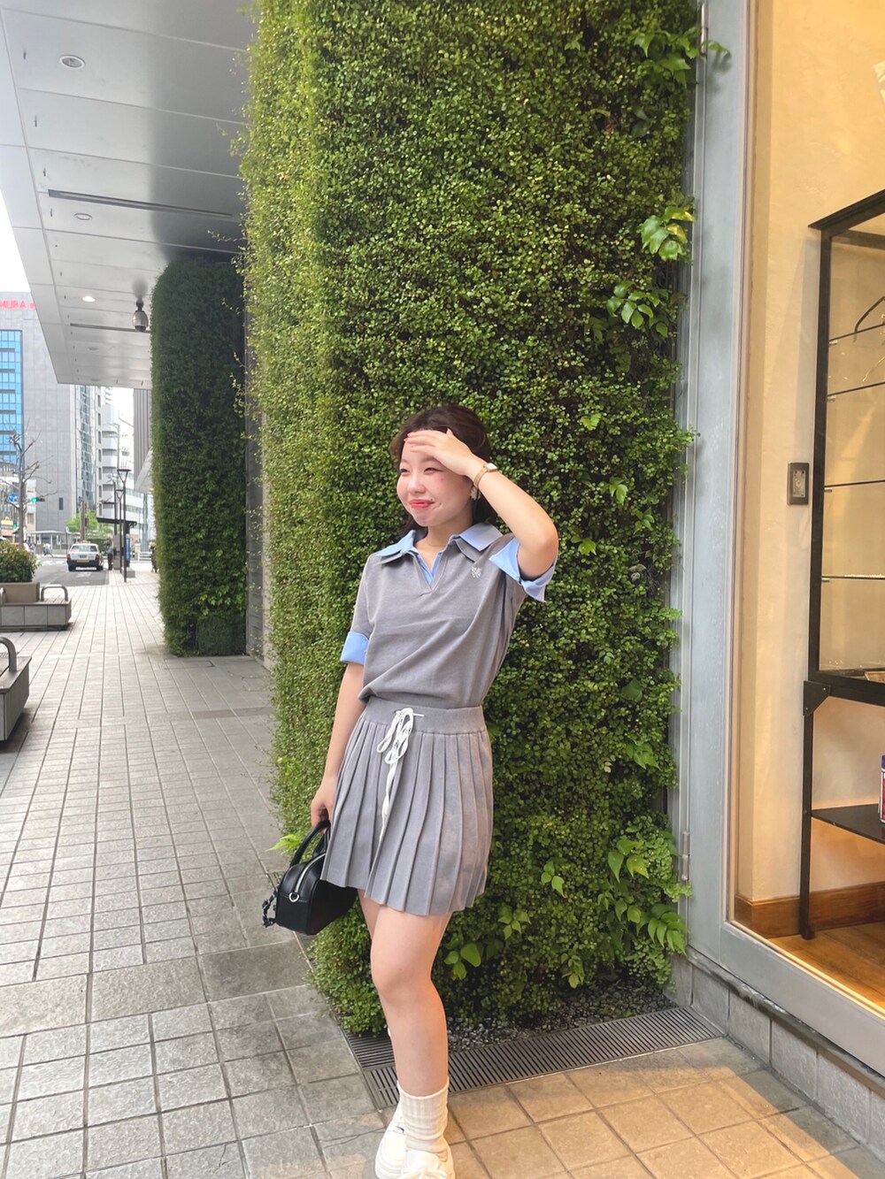 グレー系のニット/セーター、グレー系のスカート、ホワイト系のスニーカーを着用したレディースの春コーディネートの4枚目の写真