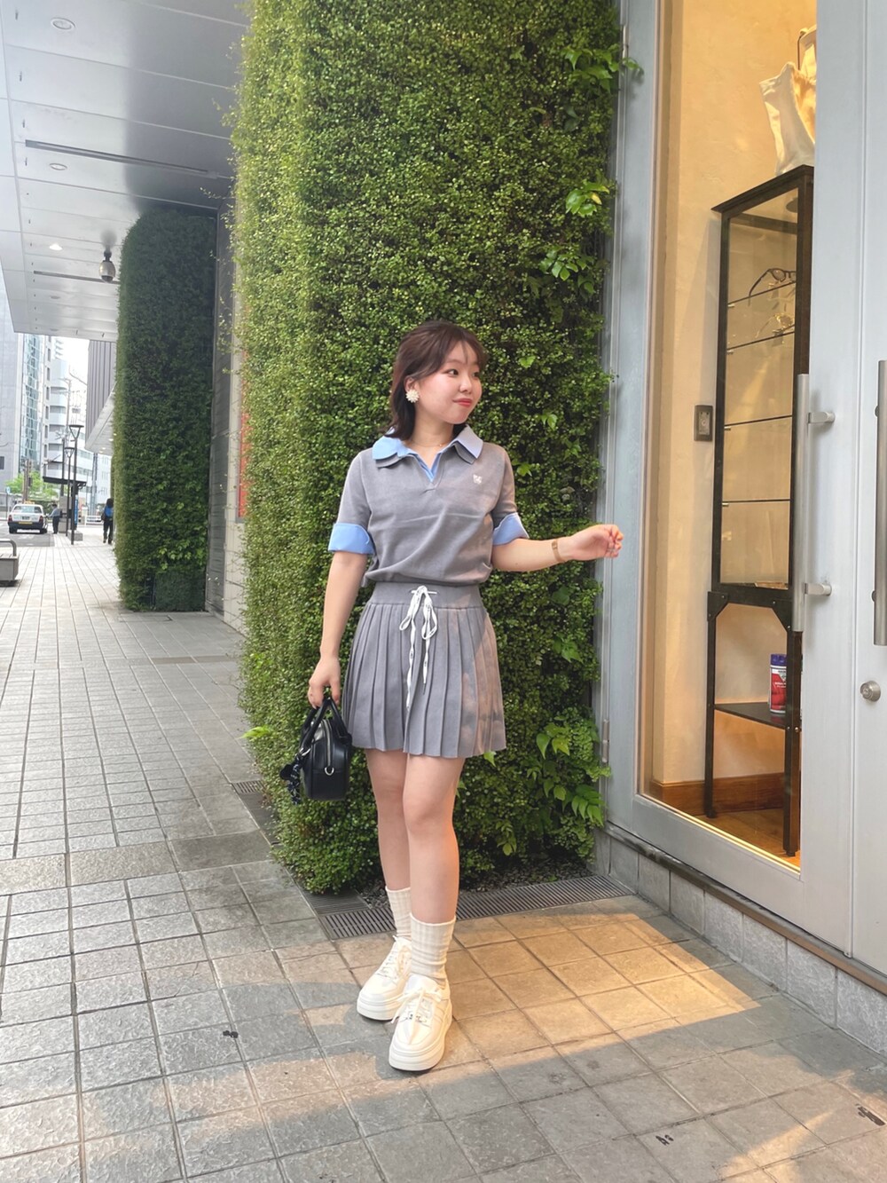 グレー系のニット/セーター、グレー系のスカート、ホワイト系のスニーカーを着用したレディースの春コーディネートの3枚目の写真