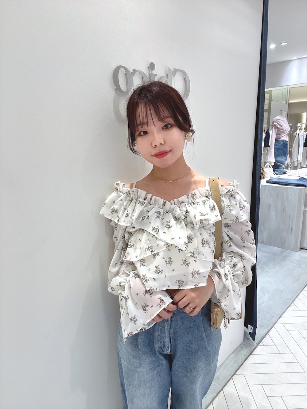 ホワイト系のシャツ/ブラウス、ベージュ系のショルダーバッグ、ブルー系のデニムパンツを着用したレディースの春コーディネートの2枚目の写真