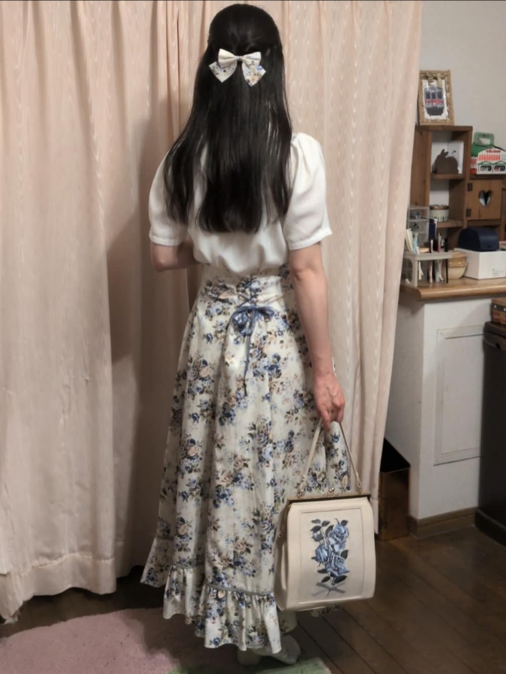 ブルー系のスカート、ホワイト系のハンドバッグ、ホワイト系のシャツ/ブラウスを着用したレディースの秋コーディネートの2枚目の写真