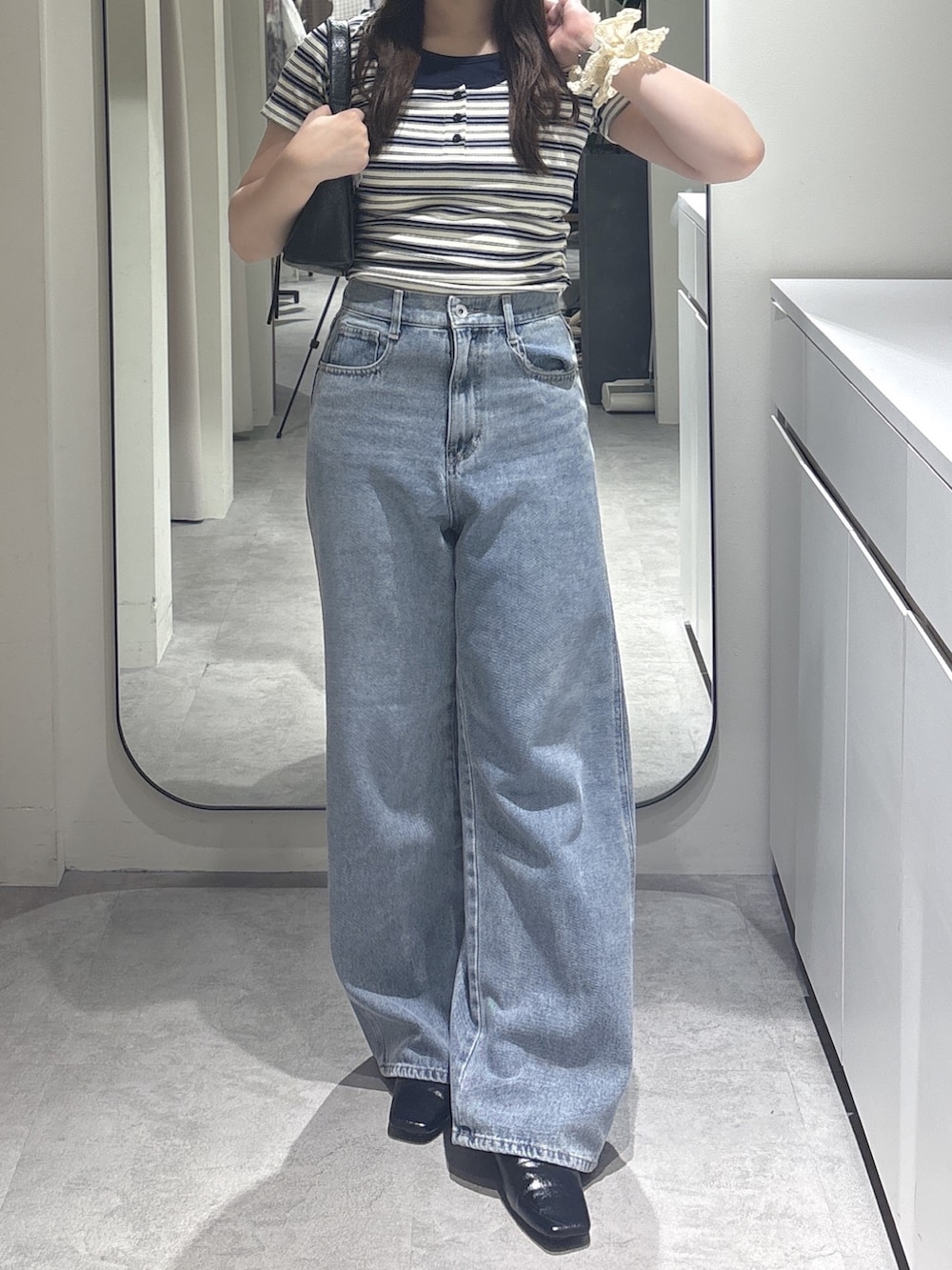 ホワイト系のTシャツ/カットソー、ブルー系のデニムパンツ、ブラック系のショルダーバッグを着用したレディースの夏コーディネートの4枚目の写真