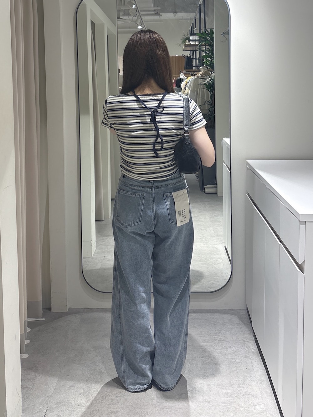 ホワイト系のTシャツ/カットソー、ブルー系のデニムパンツ、ブラック系のショルダーバッグを着用したレディースの夏コーディネートの3枚目の写真