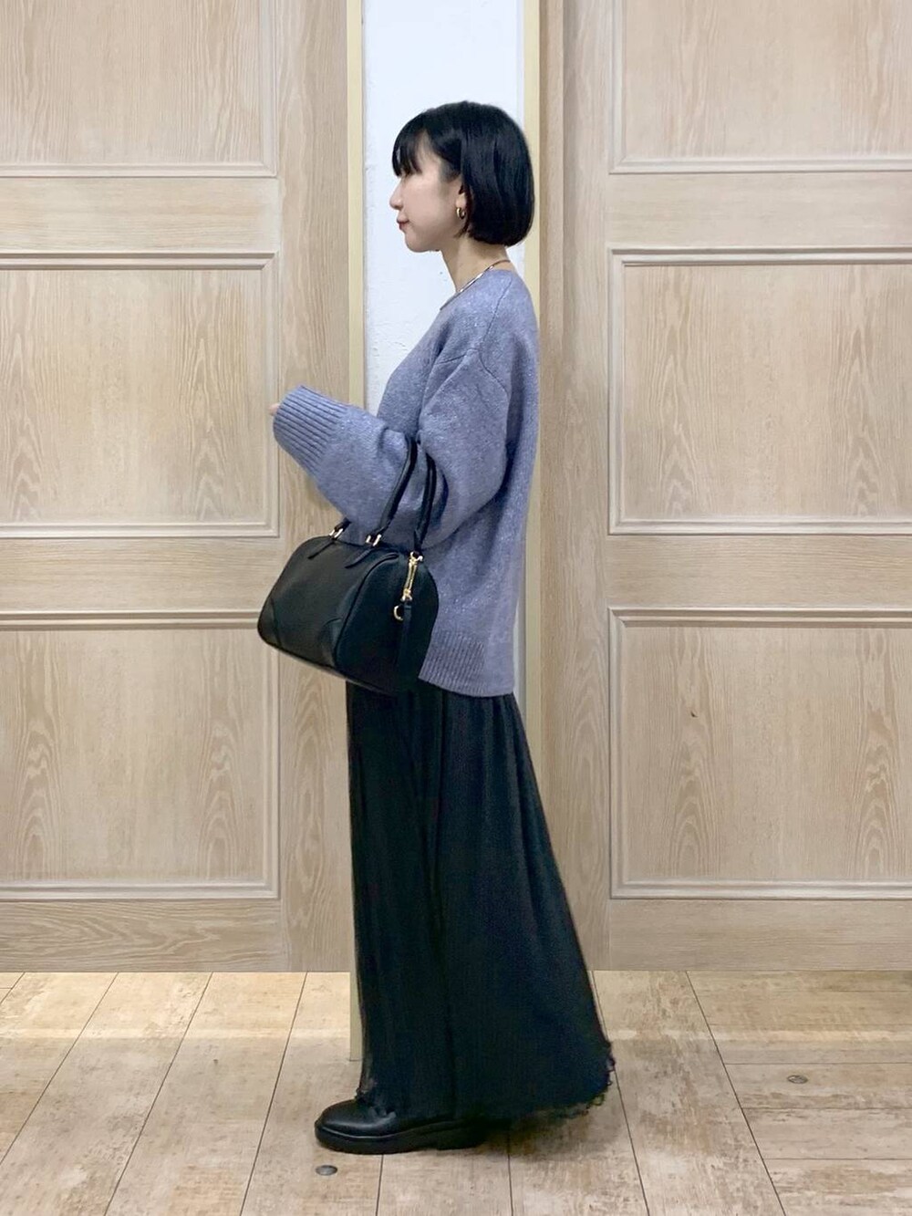 ブラック系のボストンバッグ、ブラック系のブーツを着用したレディースの冬コーディネートの2枚目の写真