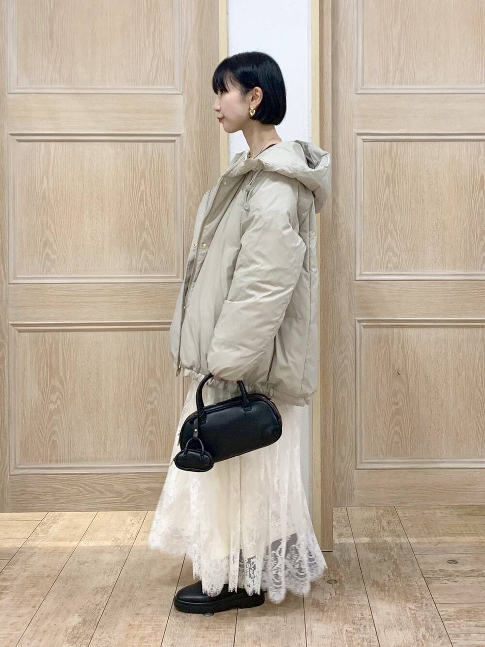 ベージュ系のダウンジャケット/コート、ブラウン系のワンピース、ブラック系のハンドバッグを着用したレディースの秋コーディネートの2枚目の写真