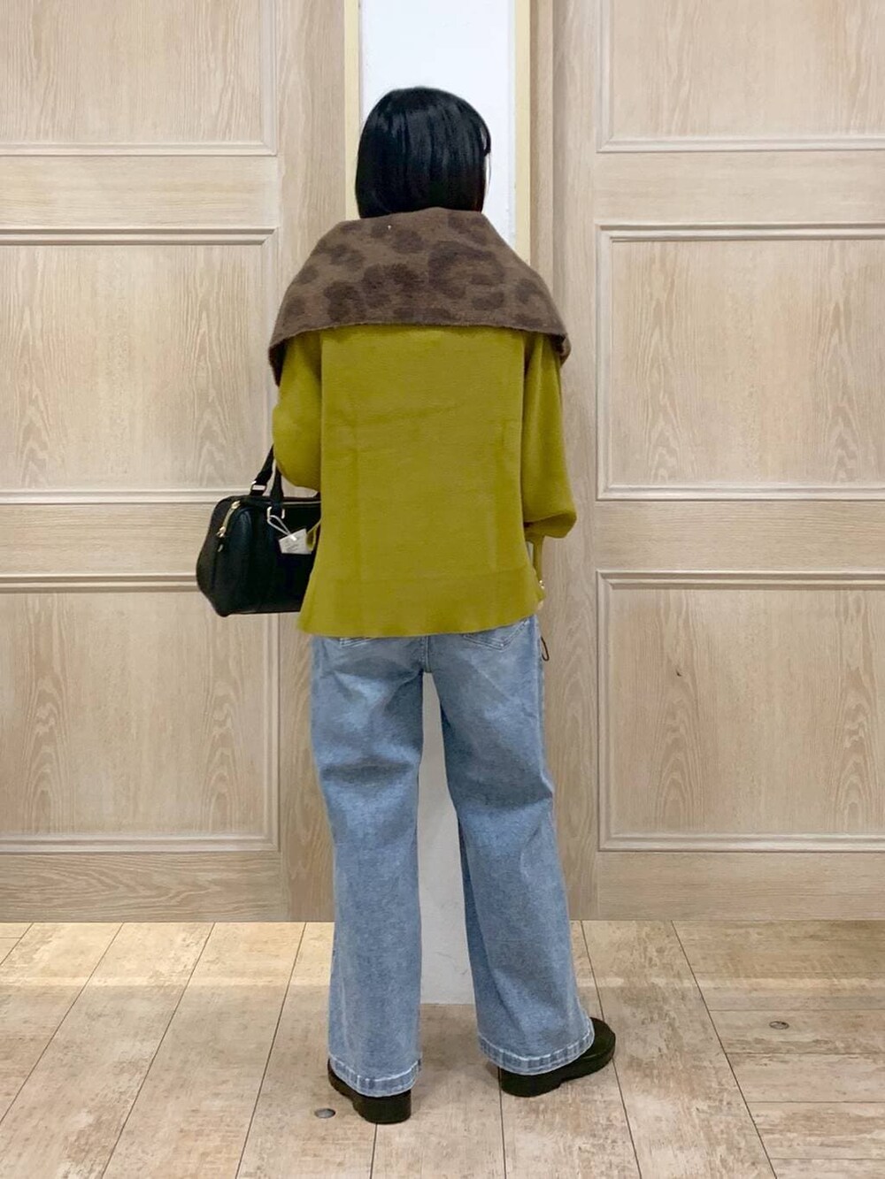 イエロー系のニット/セーター、ブラック系のボストンバッグ、ブルー系のデニムパンツを着用したレディースの秋コーディネートの3枚目の写真