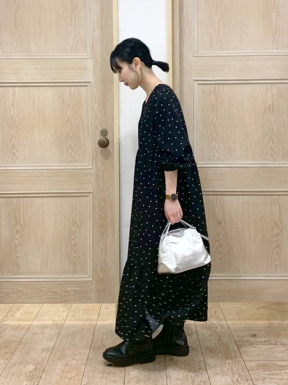 シルバー系のショルダーバッグ、ブラック系のブーツ、ブラック系のワンピースを着用したレディースの冬コーディネートの2枚目の写真