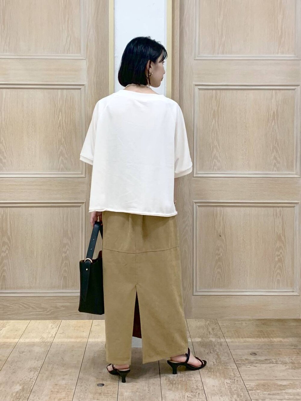 ブラック系のショルダーバッグ、ブラック系のサンダル、ベージュ系のTシャツ/カットソーを着用したレディースの秋コーディネートの3枚目の写真