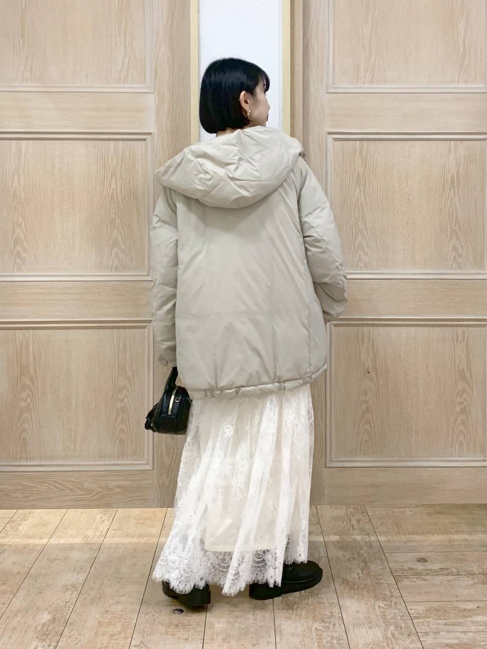 ベージュ系のダウンジャケット/コート、ブラウン系のワンピース、ブラック系のハンドバッグを着用したレディースの秋コーディネートの3枚目の写真