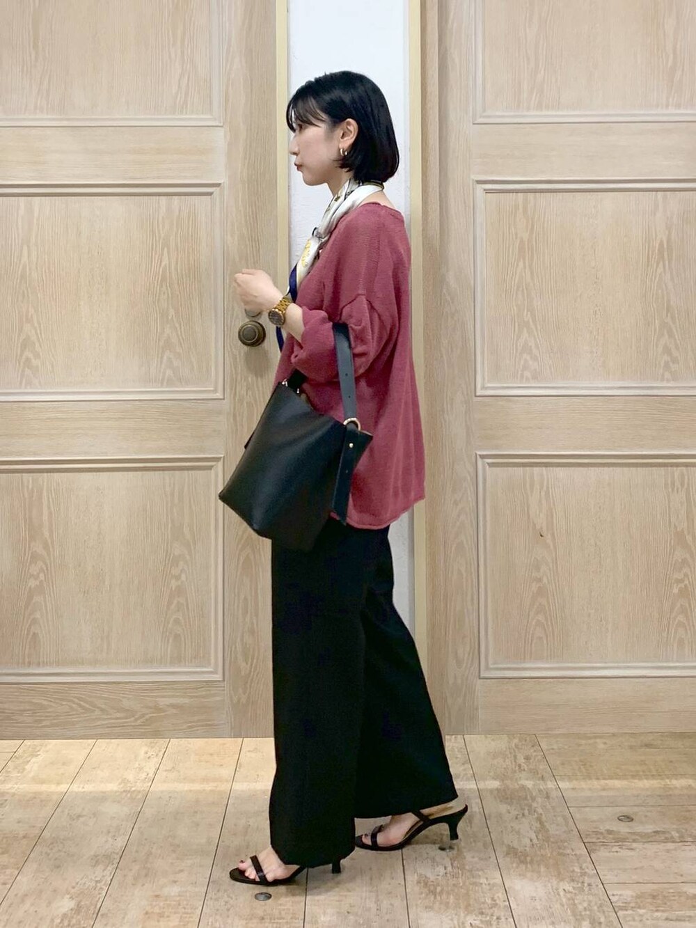 ブラック系のショルダーバッグ、ブラック系のサンダル、レッド系のニット/セーターを着用したレディースの秋コーディネートの2枚目の写真