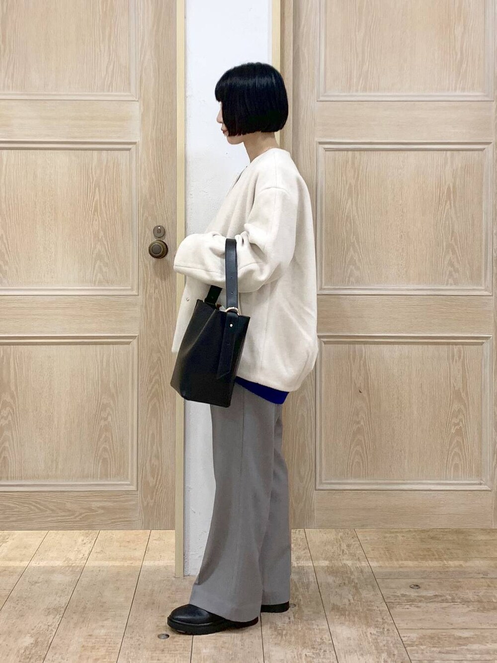 ブラック系のショルダーバッグ、ベージュ系のノーカラーコート、グレー系のその他パンツを着用したレディースの秋コーディネートの2枚目の写真