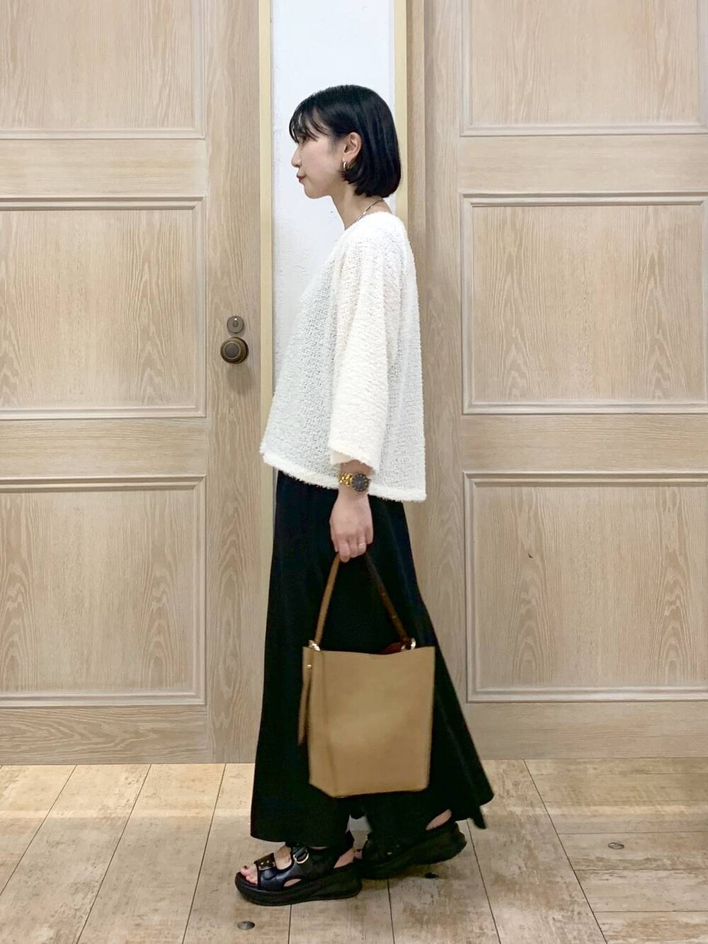 ブラウン系のショルダーバッグ、ブラック系のサンダル、ベージュ系のTシャツ/カットソーを着用したレディースの秋コーディネートの2枚目の写真