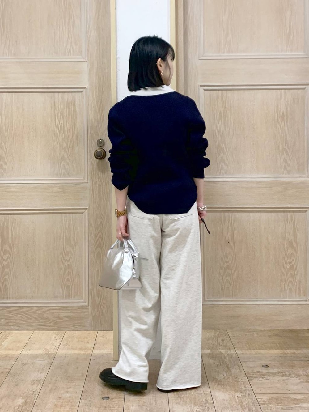 シルバー系のショルダーバッグ、ブラック系のブーツ、ホワイト系のスウェットパンツを着用したレディースの冬コーディネートの3枚目の写真