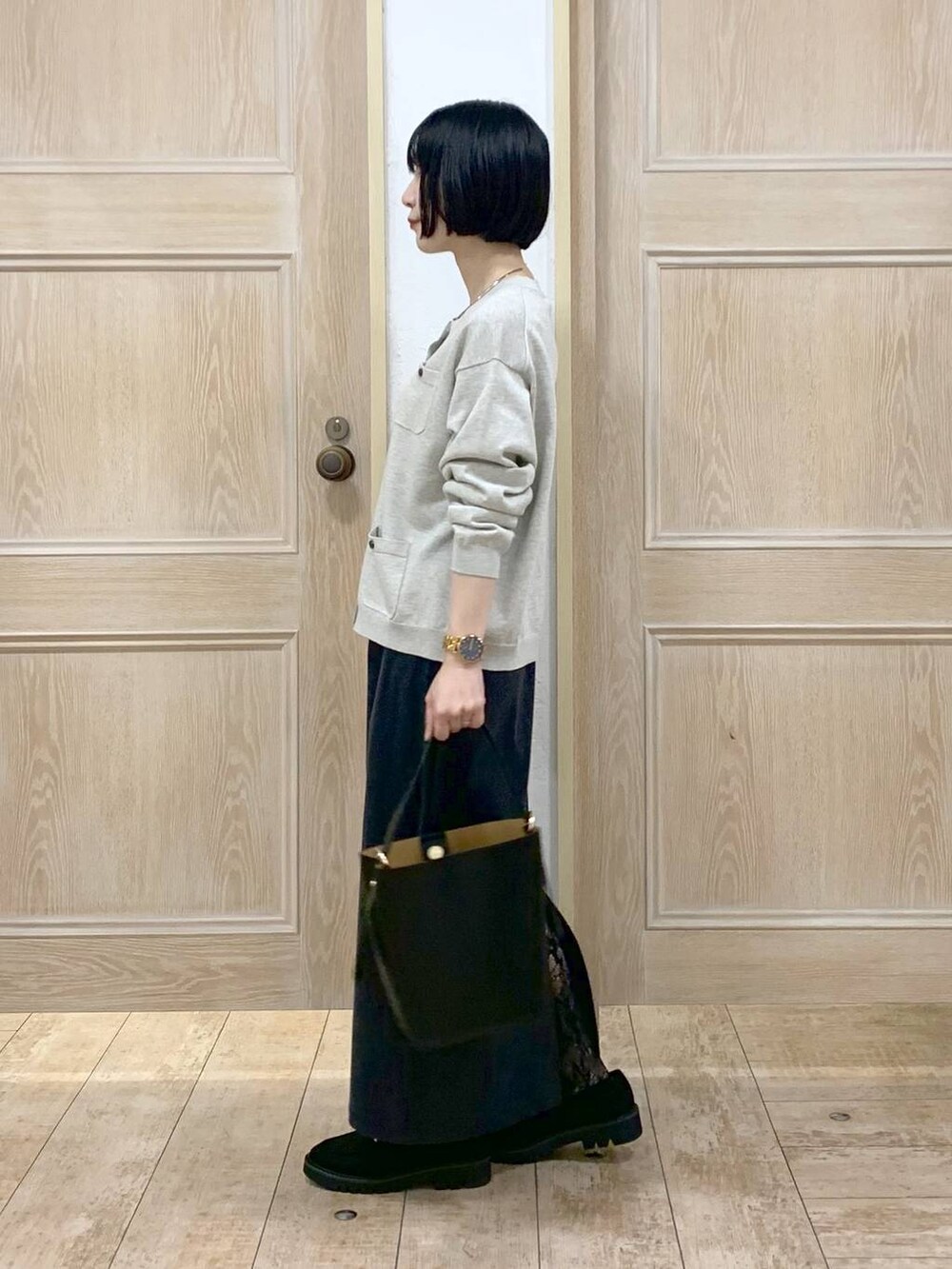 ブラック系のショルダーバッグ、グレー系のスカート、ブラック系のローファーを着用したレディースの秋コーディネートの2枚目の写真