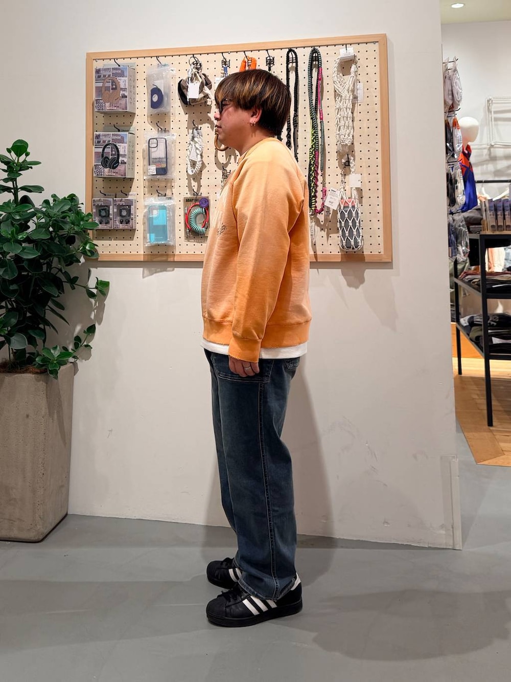 ブラック系のその他シューズ、ブルー系のデニムパンツ、オレンジ系のスウェットを着用したメンズの春コーディネートの3枚目の写真