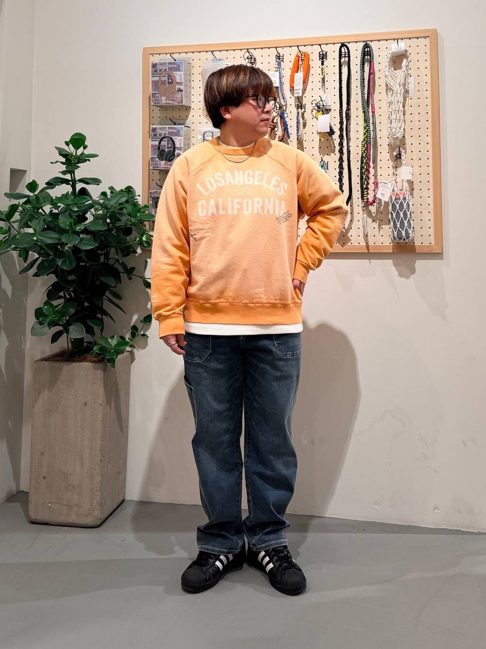 ブラック系のその他シューズ、ブルー系のデニムパンツ、オレンジ系のスウェットを着用したメンズの春コーディネートの2枚目の写真