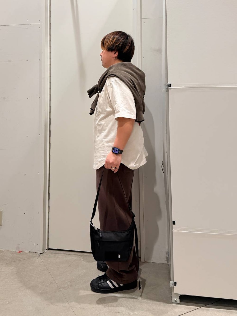 ブラック系のその他シューズ、ホワイト系のTシャツ/カットソー、ブラック系のショルダーバッグを着用したメンズの春コーディネートの2枚目の写真