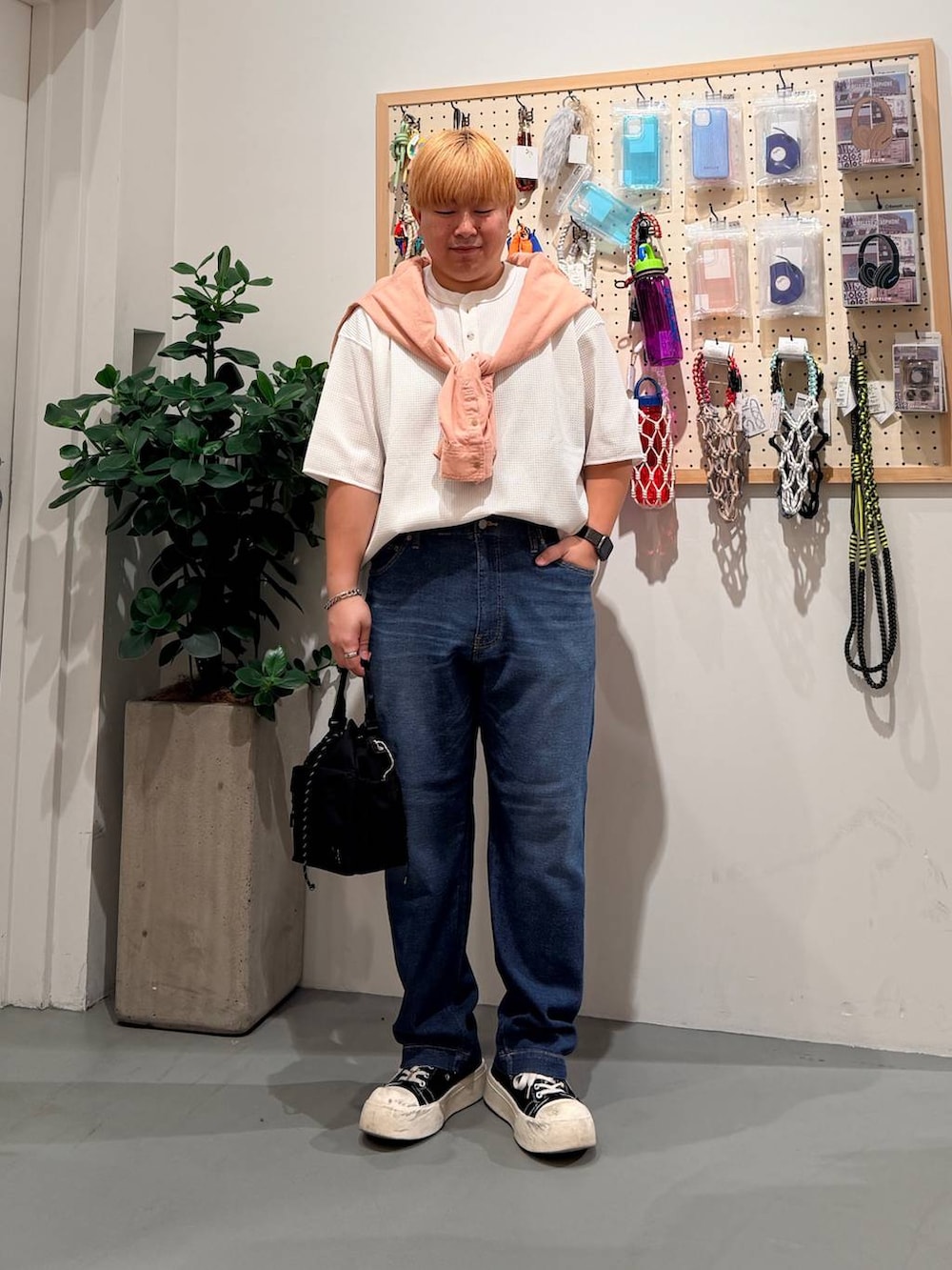 ブルー系のデニムパンツ、オレンジ系のシャツ/ブラウス、ブラック系のショルダーバッグを着用したメンズの春コーディネートの2枚目の写真