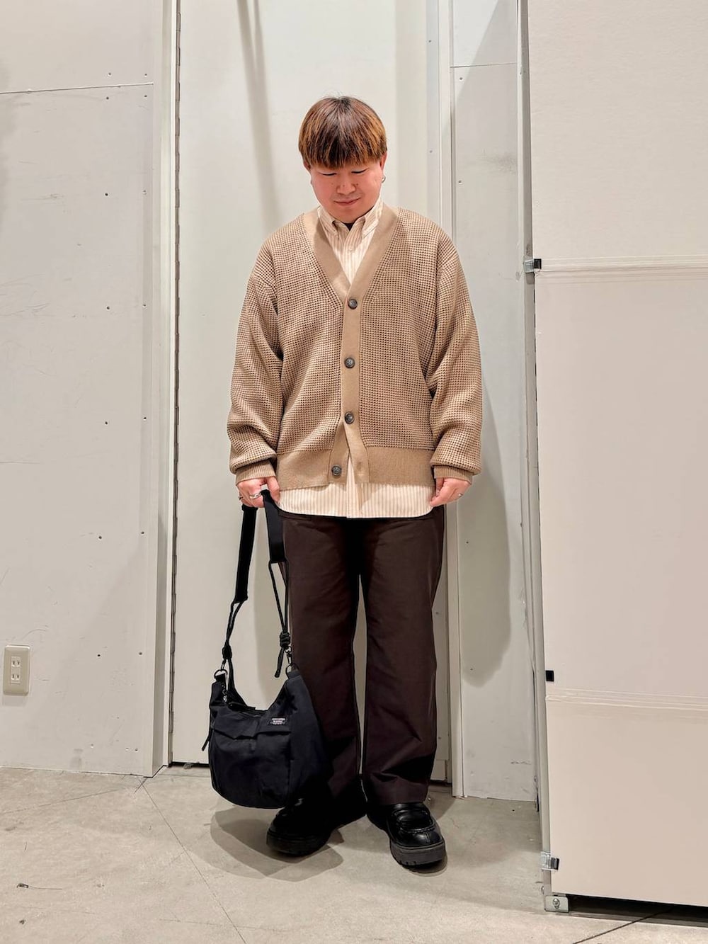 ブラック系のショルダーバッグ、ベージュ系のカーディガン/ボレロ、ベージュ系のシャツ/ブラウスを着用したメンズの冬コーディネートの2枚目の写真