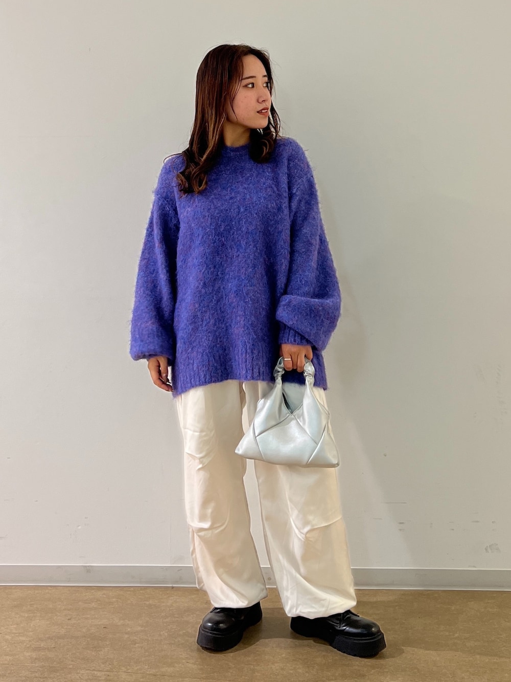 ブルー系のニット/セーター、ホワイト系のカーゴパンツ、シルバー系のショルダーバッグを着用したレディースの秋コーディネートの2枚目の写真