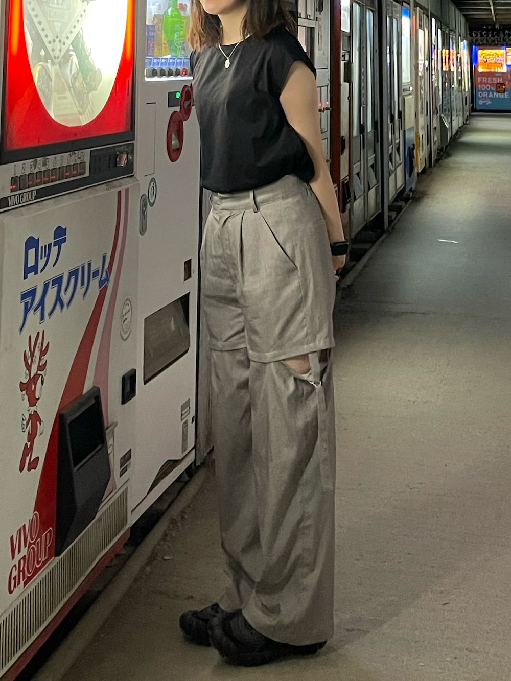 ブラック系のTシャツ/カットソー、グレー系のスラックス、ブラック系のスニーカーを着用したレディースの夏コーディネートの2枚目の写真