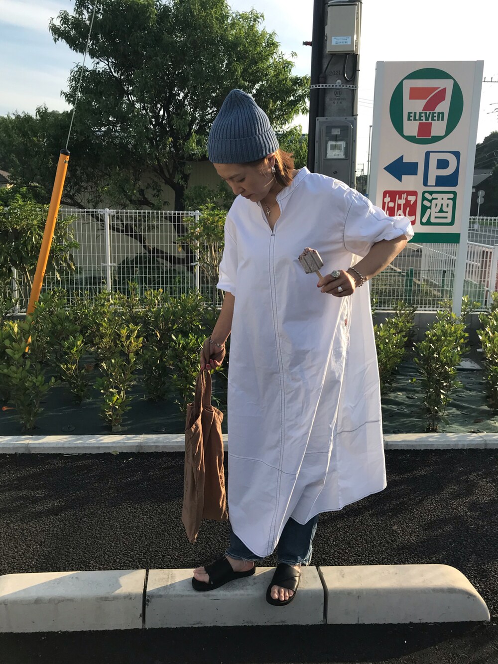 ホワイト系のワンピース、ベージュ系のトートバッグ、ブラック系のサンダルを着用したレディースの春コーディネートの2枚目の写真