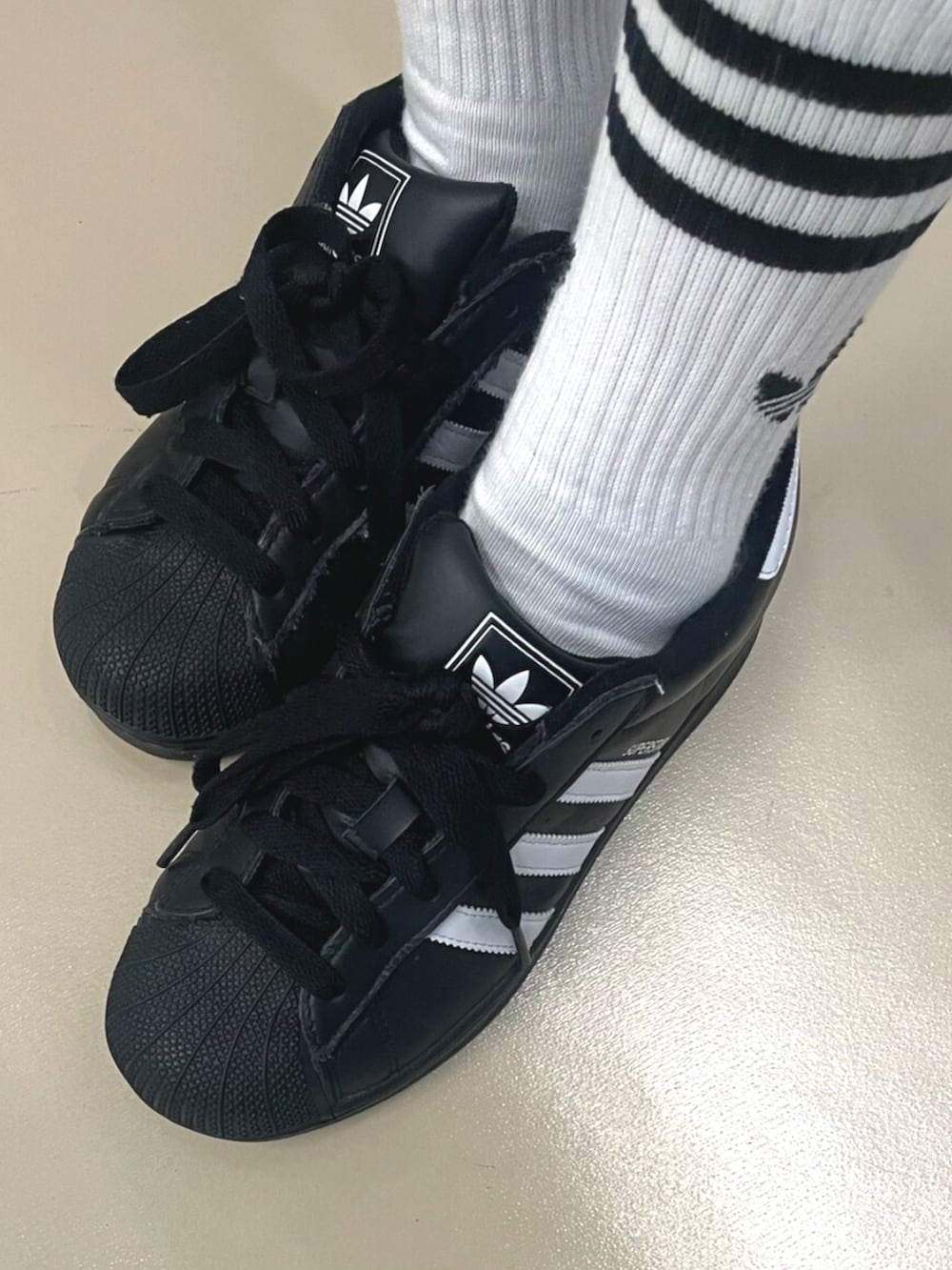 ブラック系のスニーカー、ブルー系のデニムスカート、グレー系のポロシャツを着用したレディースの秋コーディネートの2枚目の写真