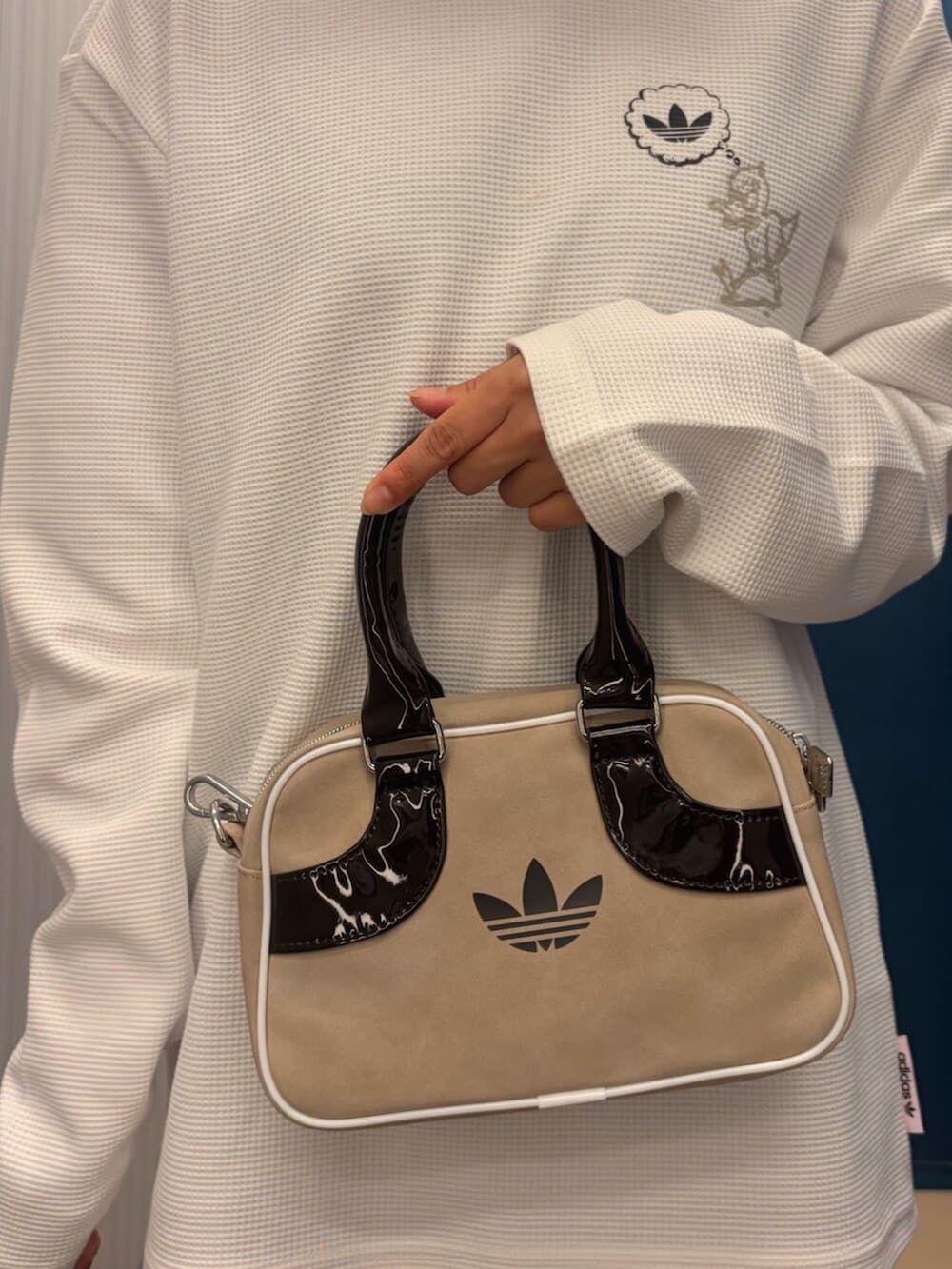 ホワイト系のTシャツ/カットソー、ベージュ系のスニーカー、ブラウン系のショルダーバッグを着用したレディースの冬コーディネートの3枚目の写真